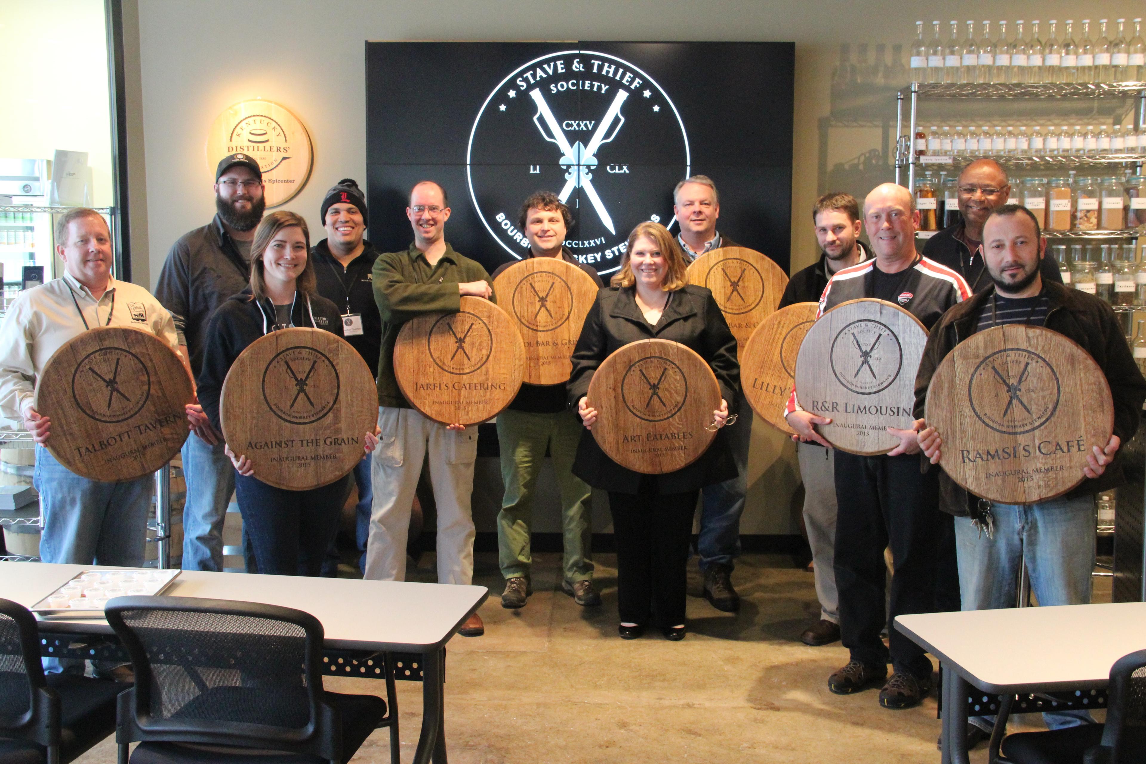 People posing with commemorative barrel heads.