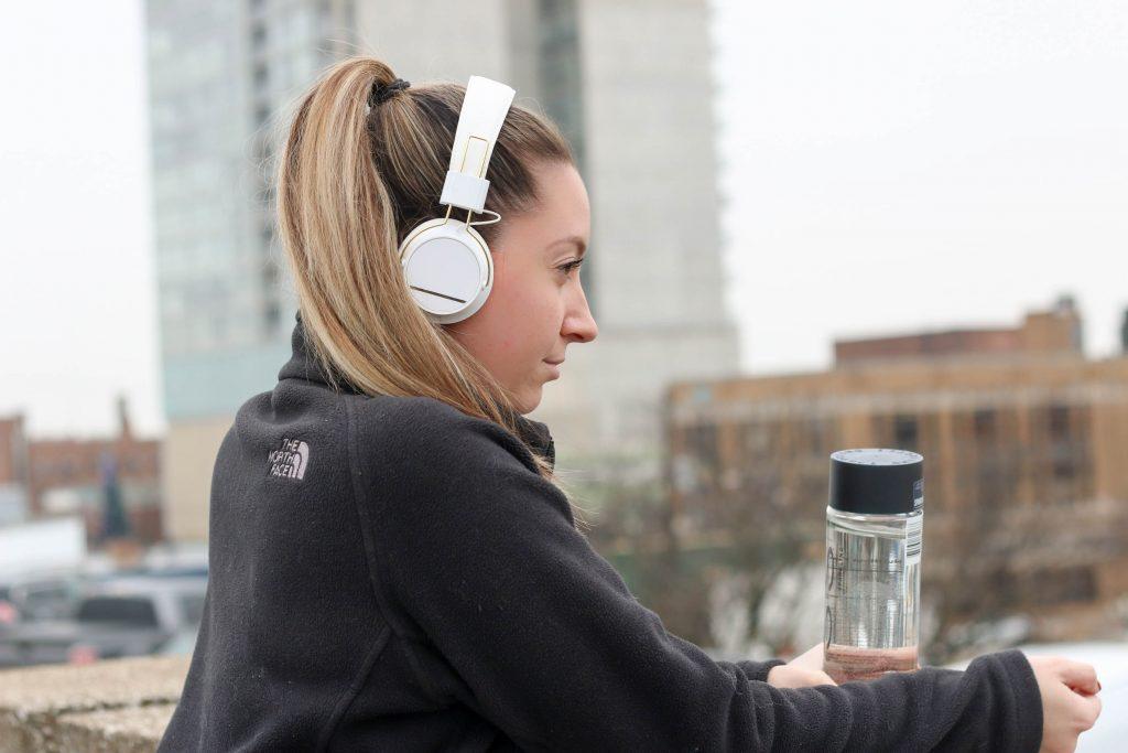 woman working out with headphones and voss water 