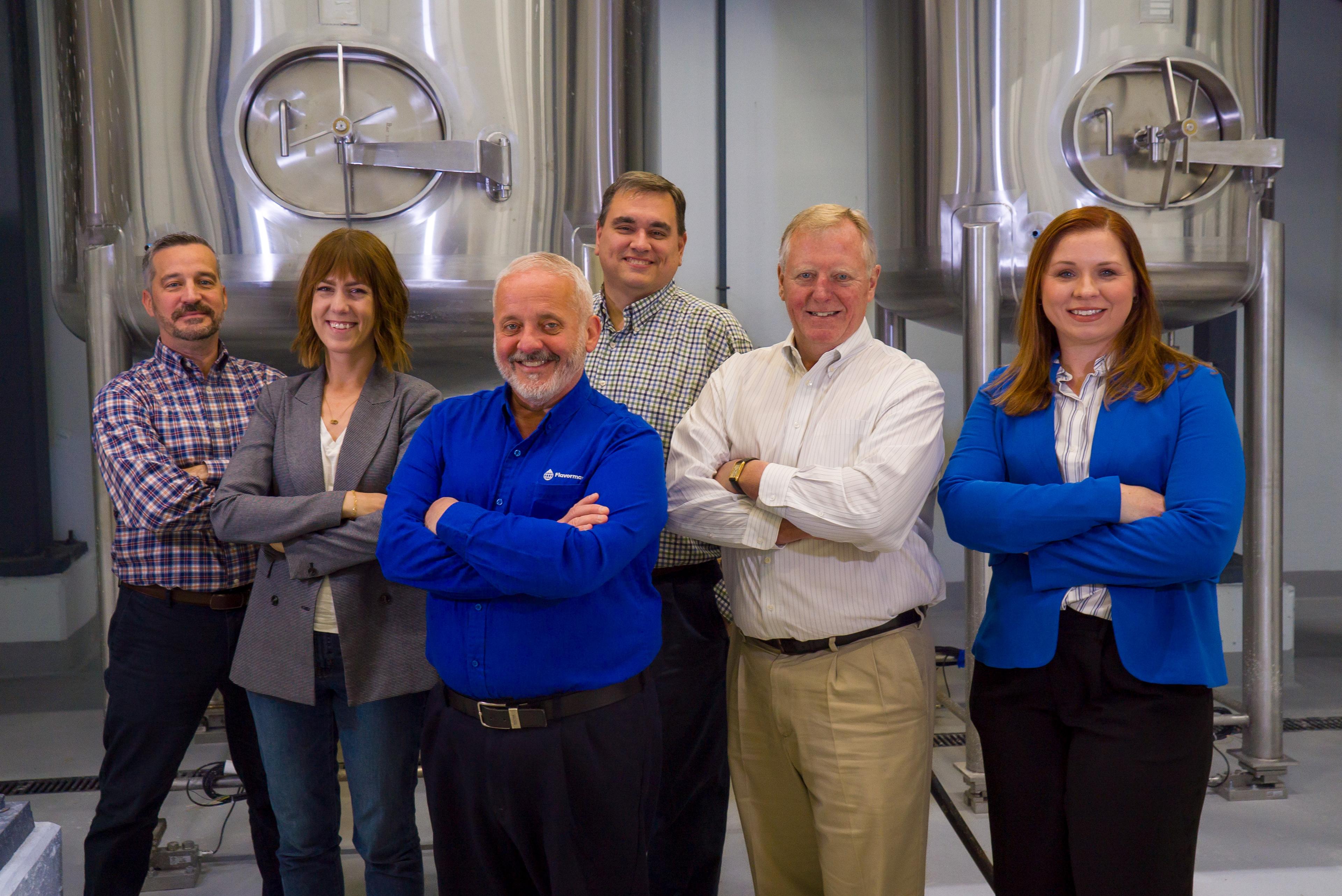 Flavorman employees posing in front of tanks