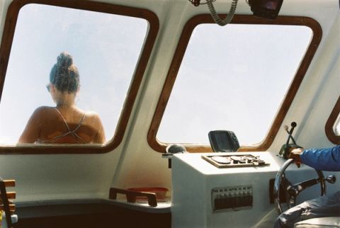 Une femme à l'avant d'un bateau avec un capitaine à la barre