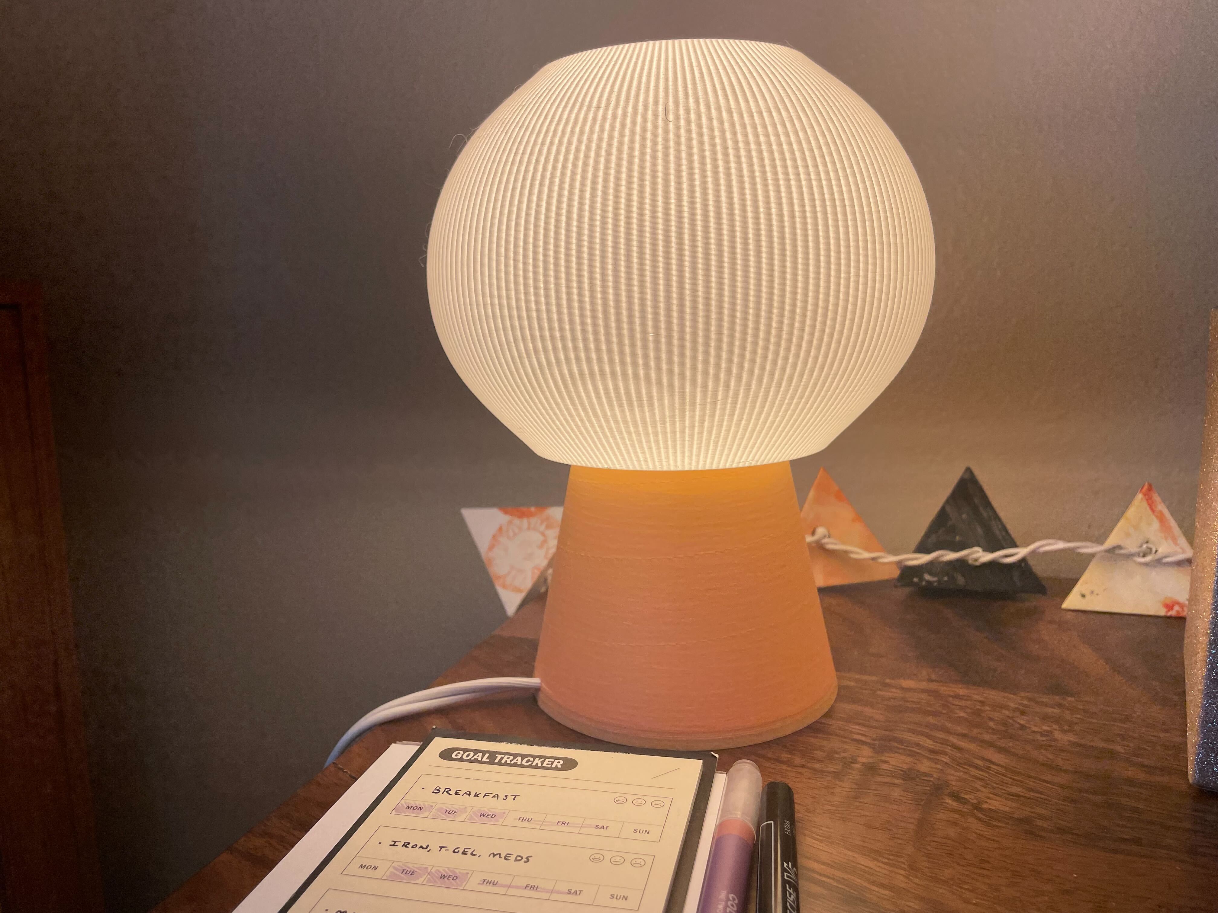 A small, soft lamp with a peach base and yellow, spherical pleated shade.