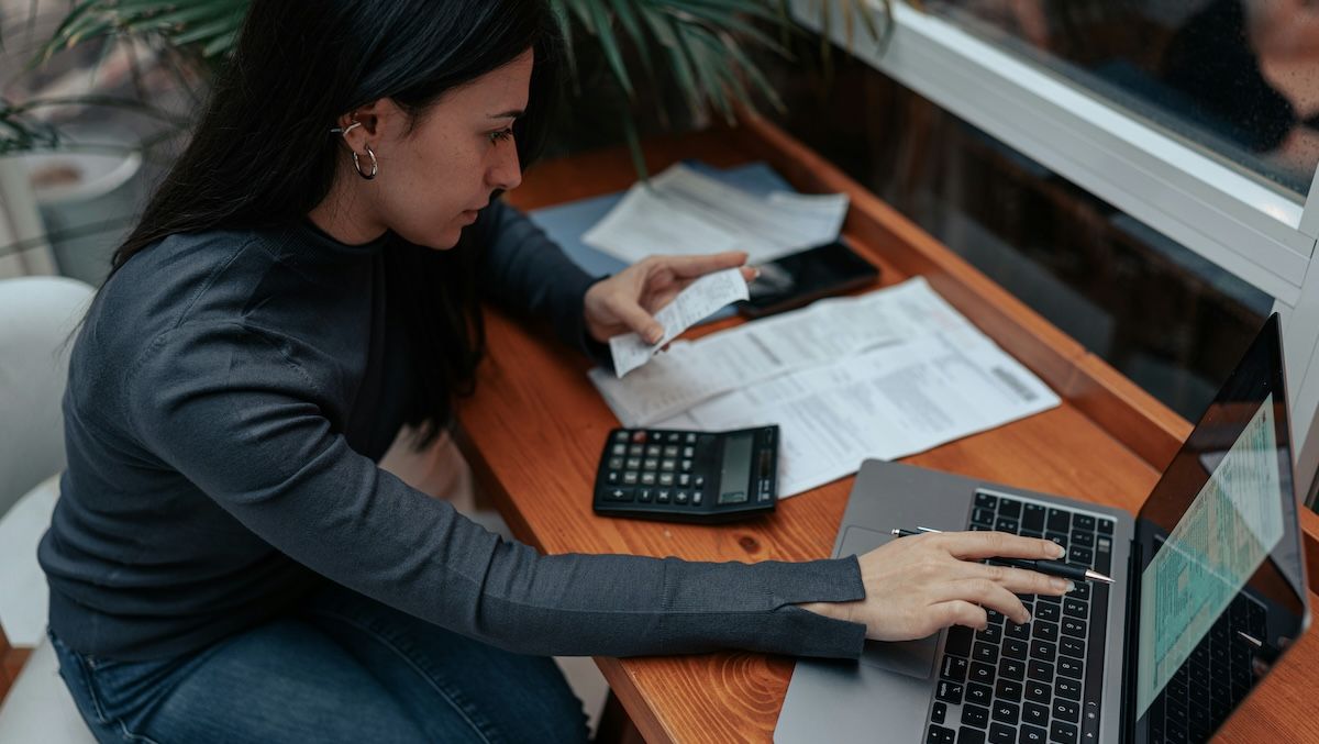 a woman sitting at her desk at home trying to cope with tax anxiety as she looks through reciepts