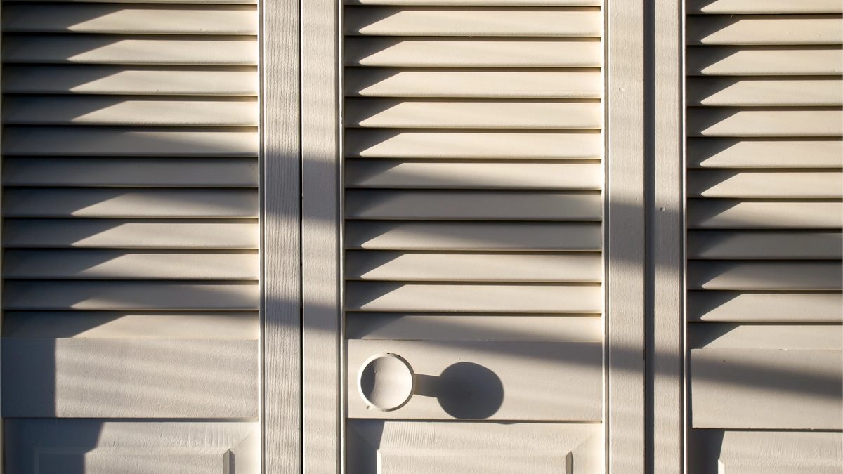 Closed closet doors thrown into relief by shadows from bright afternoon sunlight.