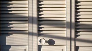 Closed closet doors thrown into relief by shadows from bright afternoon sunlight.