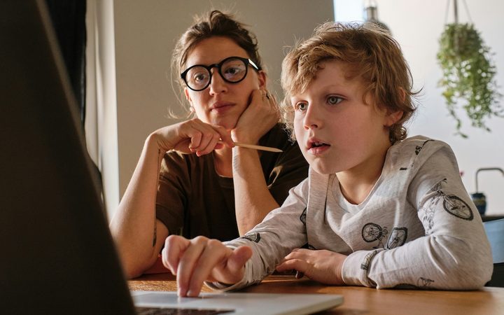 A mother and son sit a laptop, looking for a pediatric therapist