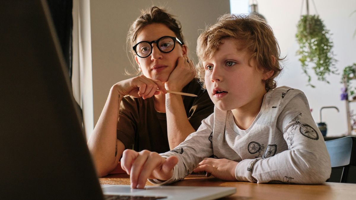 A mother and son sit a laptop, looking for a pediatric therapist