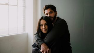A man standing behind a woman with his arms wrapped around her shoulders