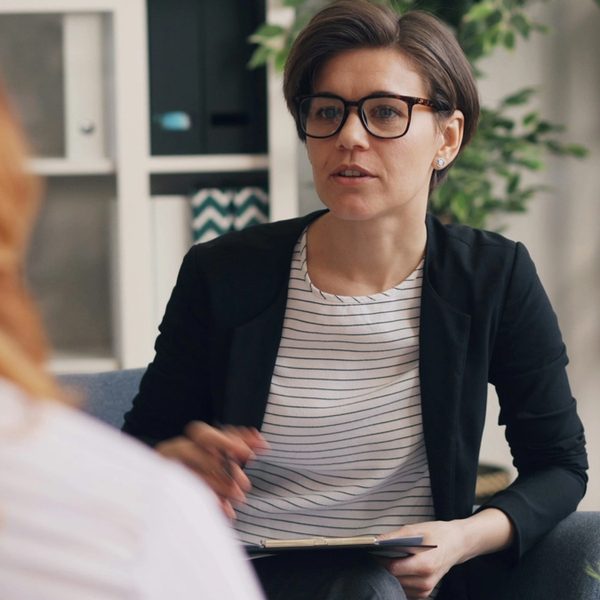 Therapist speaking with a client during a counseling session in an office.
