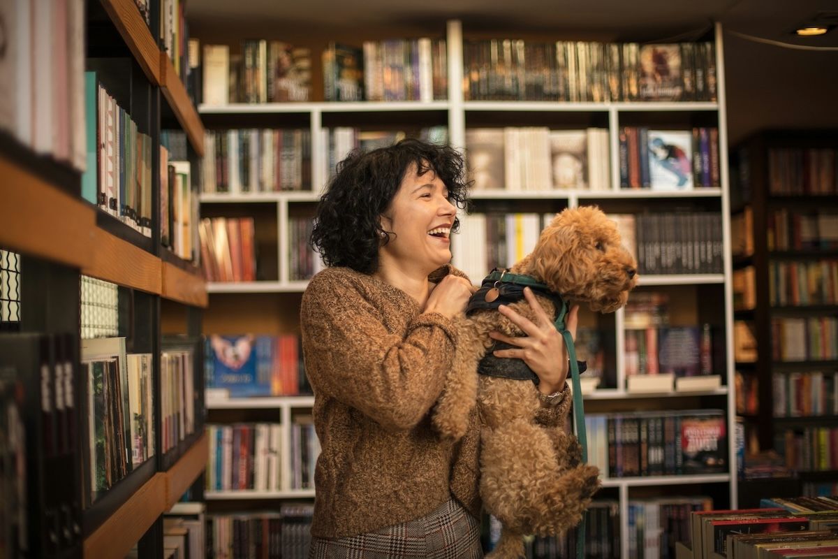 a therapist in a bookstore holding her dog in her arms and laughing