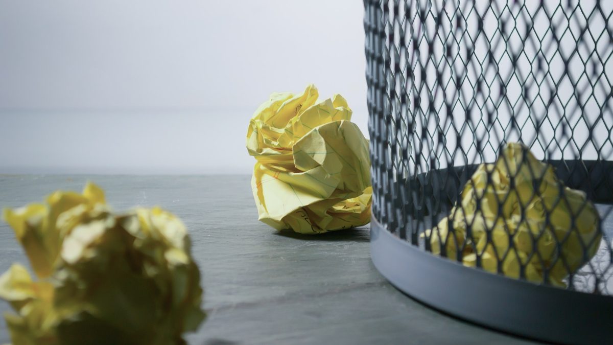Rejected ideas, shown as crumpled pieces of paper aimed for the trash bin.