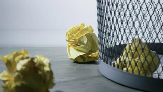 Rejected ideas, shown as crumpled pieces of paper aimed for the trash bin.