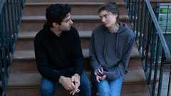 A couple is sitting on the stoop of a brownstone having an important conversation