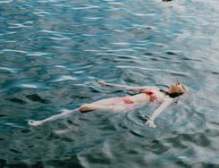A swimmer floats on open waters, striking the delicate balance between resting and drowning.