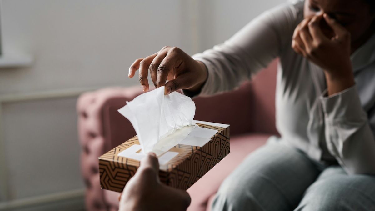 a crying woman reaches for tissue in a therapy session