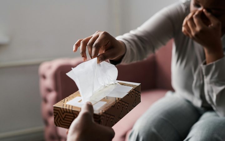 a crying woman reaches for tissue in a therapy session