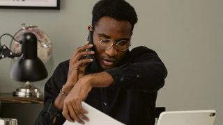 A mental health therapist doing admin work in their office, on the phone with an insurance provider