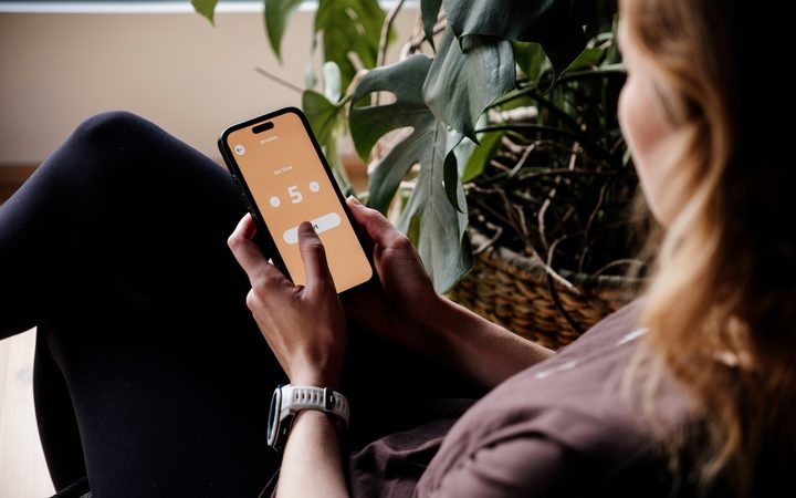 A woman sitting in a chair, using a meditation app to help reach her mental health goals.