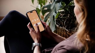 A woman sitting in a chair, using a meditation app to help reach her mental health goals.