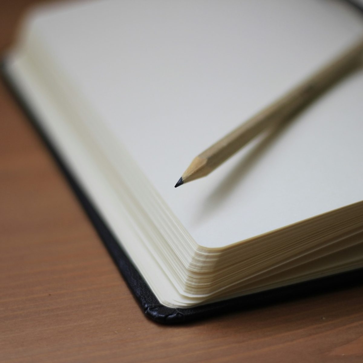 A close-up of a notebook and pencil on a desk
