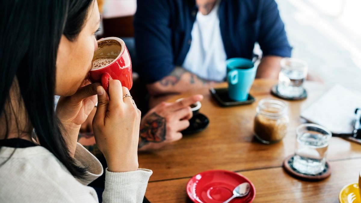 a woman sips from a coffee cup at a social gathering