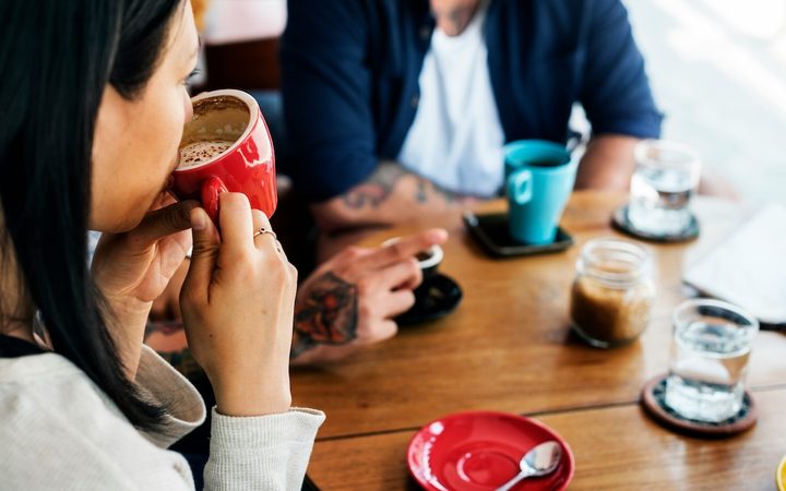 a woman sips from a coffee cup at a social gathering