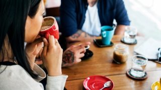 a woman sips from a coffee cup at a social gathering