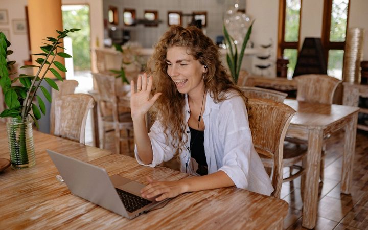 A clinician sits in front of her laptop, sitting down for a tele-therapy session.