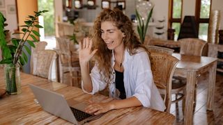 A clinician sits in front of her laptop, sitting down for a tele-therapy session.