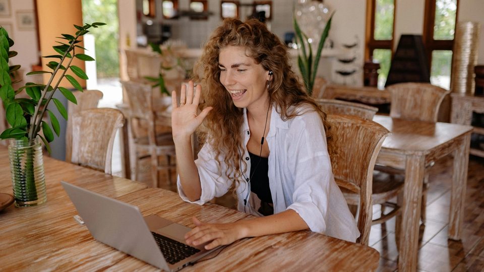 A clinician sits in front of her laptop, sitting down for a tele-therapy session.