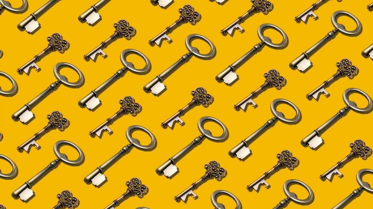 Many ornate brass keys laid flat in a perfectly repeating pattern on a marigold backdrop.