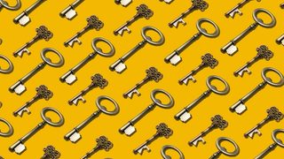 Many ornate brass keys laid flat in a perfectly repeating pattern on a marigold backdrop.