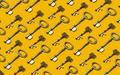 Many ornate brass keys laid flat in a perfectly repeating pattern on a marigold backdrop.