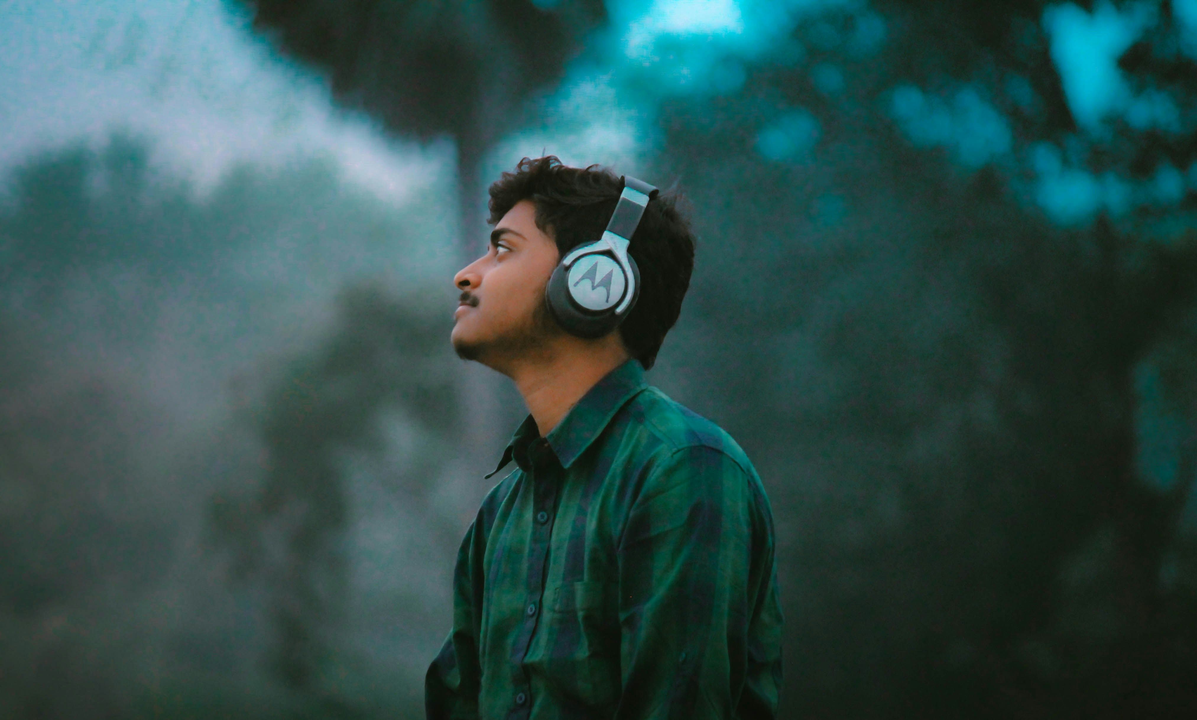 The side profile of a person in a plaid shirt standing in nature, looking at something in the distance.