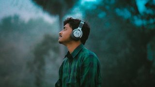The side profile of a person in a plaid shirt standing in nature, looking at something in the distance.