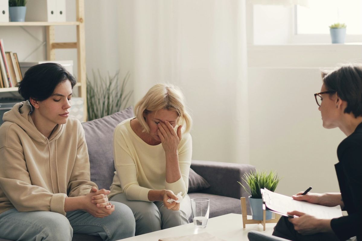 A therapist sits across from a young client and their mother