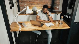 Person sitting at a desk while on the phone and looking at notes