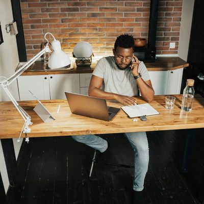 Man sitting at desk with laptop open while taking a phone call