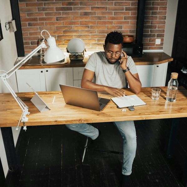 Man sitting at desk with laptop open while taking a phone call