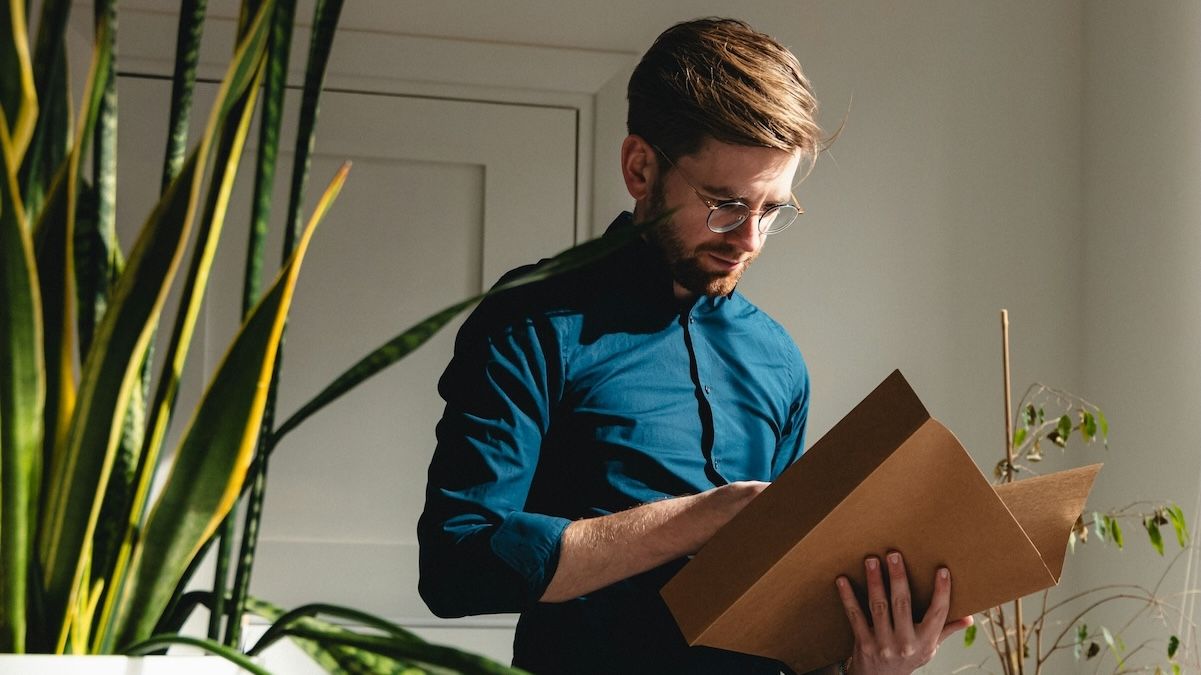 a male therapist organizes files in his sunny, plant-filled office