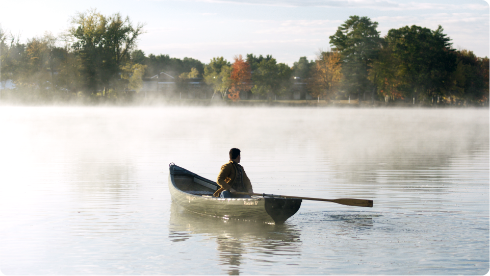 Person alone in a canoe on a misty lake