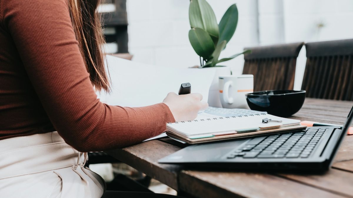 A woman is writing in font of her laptop, researching her EAP benefits