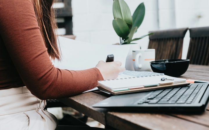 A woman is writing in font of her laptop, researching her EAP benefits