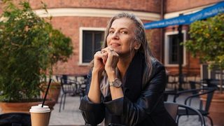 a woman sits outside of a university, considering if she should become a counselor as a second career