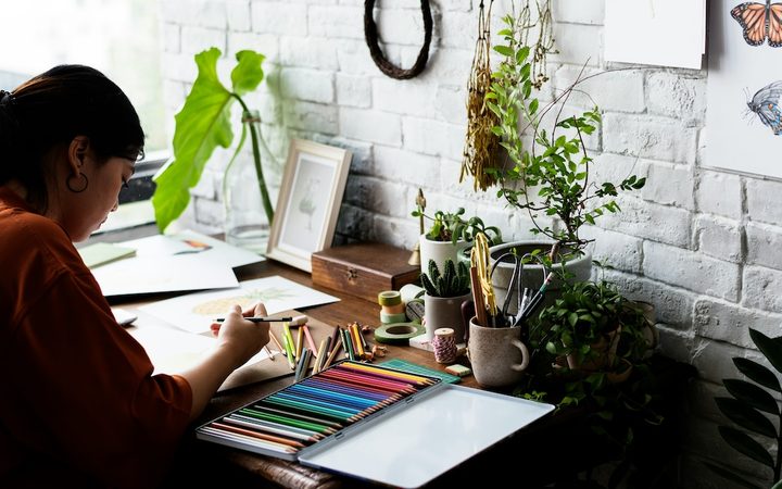 a woman creates art at home using colored pencils