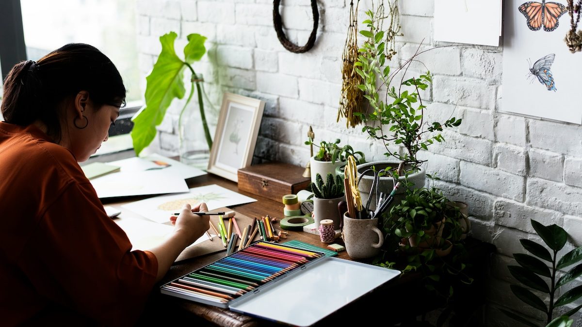 a woman creates art at home using colored pencils