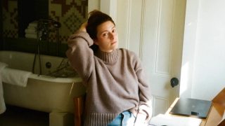 Bisexual author and playwright Haley Jakobson sits at her writing desk in Brooklyn, NY.