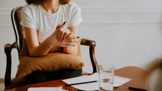 Man sitting on an orange couch speaking with a therapist who is taking notes