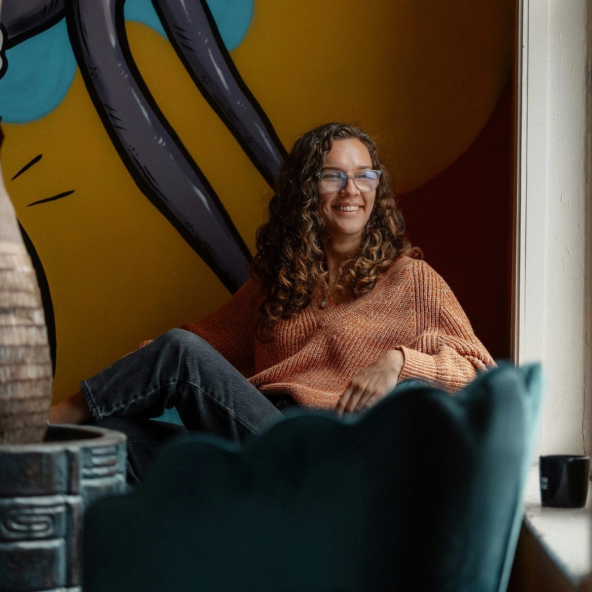 A smiling woman sitting in a chair in front of a painting