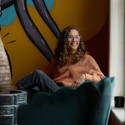 A smiling woman sitting in a chair in front of a painting