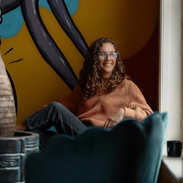 A smiling woman sitting in a chair in front of a painting